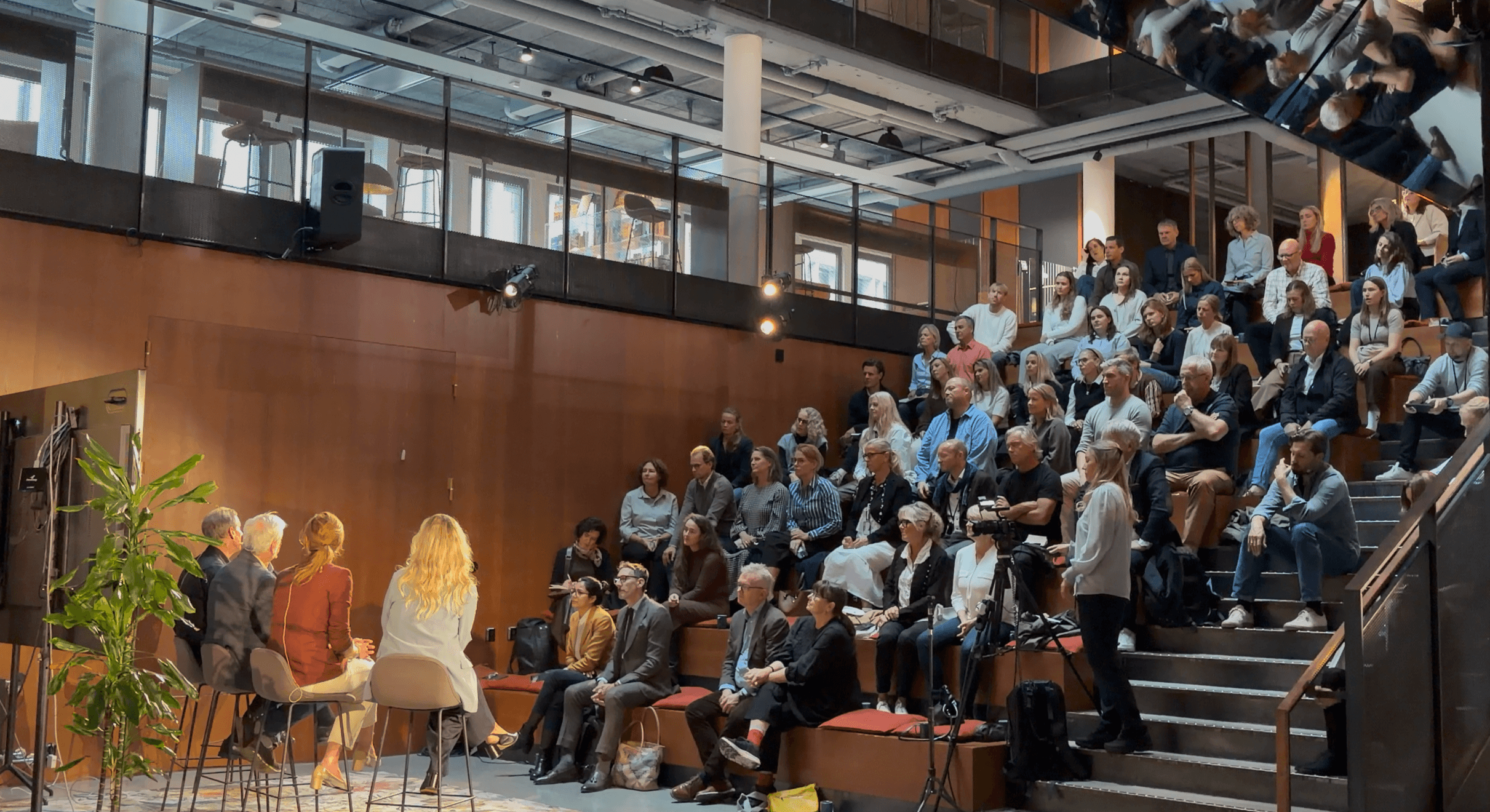Fullt podie med mennesker som ser på paneldebatt