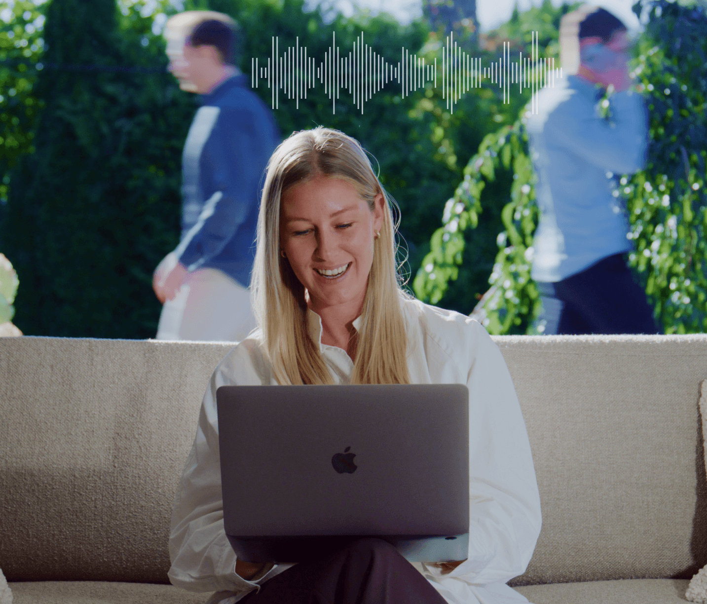 milende kvinne med hodetelefoner og laptop sitter i en sofa. Bak henne går to menn utendørs, og et lydbølgesymbol vises øverst.
